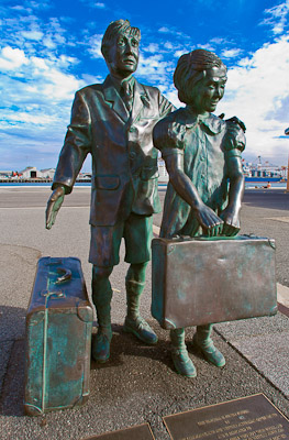 Two people standing on the quay, looking lost and helpless, not sure where to go, what to do. A small suitcase contains their worldy belongings. So here we are, what now?
